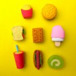 Various types of colourful food toys on a yellow background.