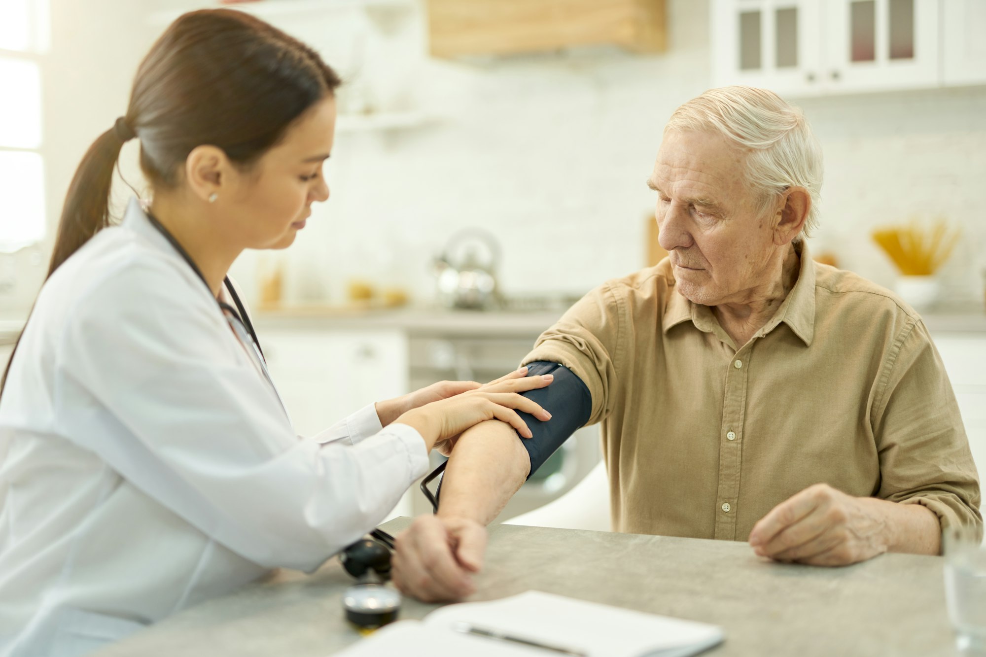 Attentive medic preparing to measure elderly man blood pressure